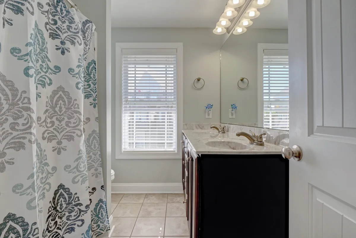 A bright bathroom with a double-sink vanity, a decorative shower curtain, and an abundance of natural light filtering through the windows. The space feels fresh and rejuvenating, perfect for morning routines or relaxing baths.