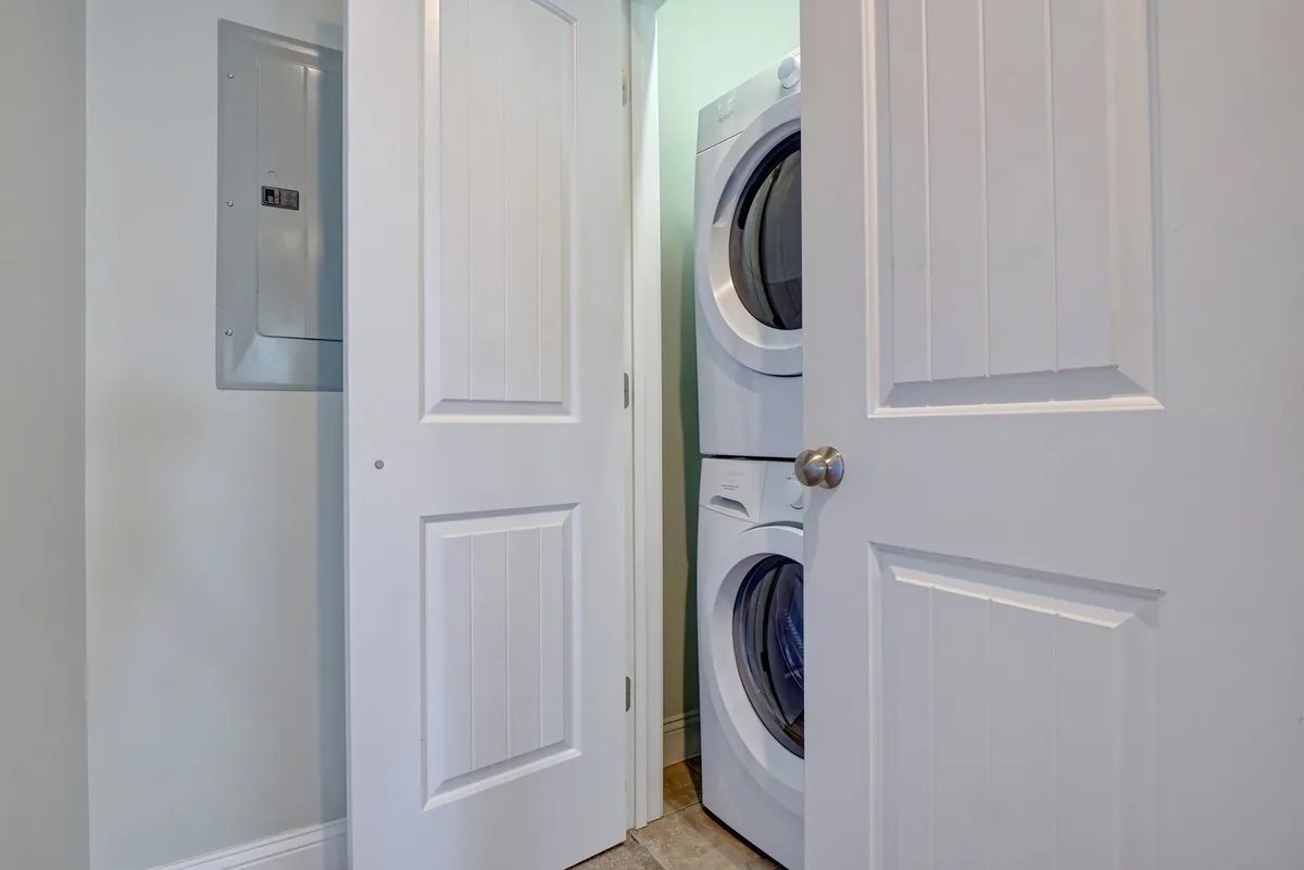 A tidy laundry area featuring a stacked washer and dryer against light-colored walls, creating an organized and practical space for doing laundry.