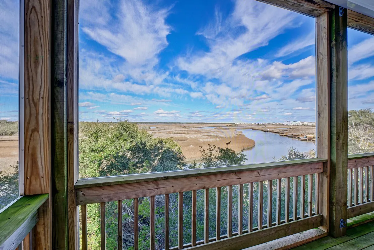 A panoramic view of the marshland and waterway, featuring a vibrant sky with dramatic clouds. The expansive vista encapsulates the natural setting that makes sunset suppers so unique, highlighting the landscape that guests enjoy from elevated dining and living areas.