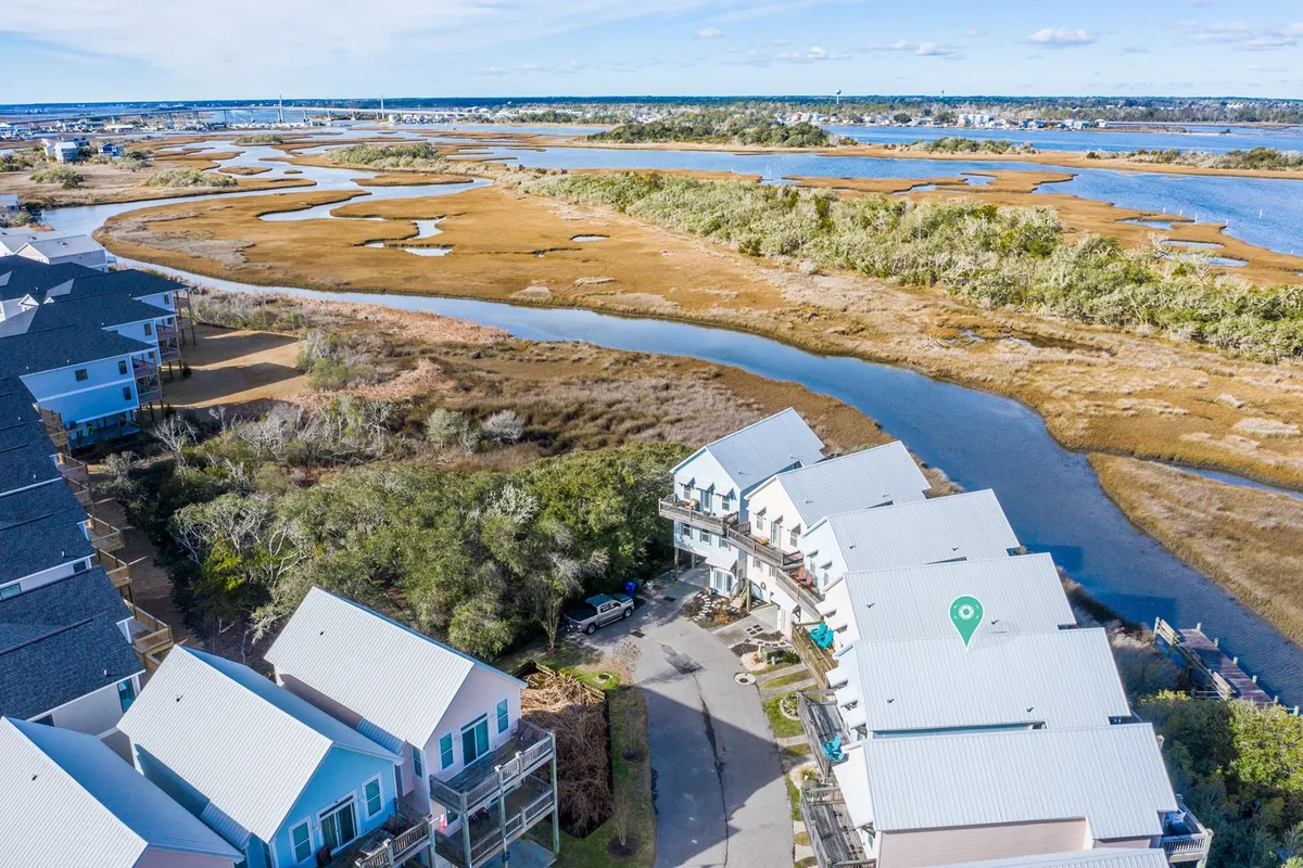 A tranquil exterior shot of a waterway bordered by marshland and townhouses, inviting activities like fishing, kayaking, birdwatching, and nature walks. The serene environment hints at exploration and relaxation possibilities.